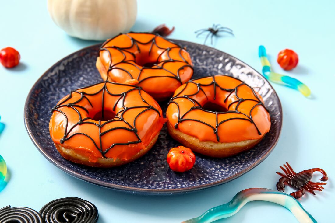 Donas glaseadas de naranja decoradas con telarañas de chocolate negro