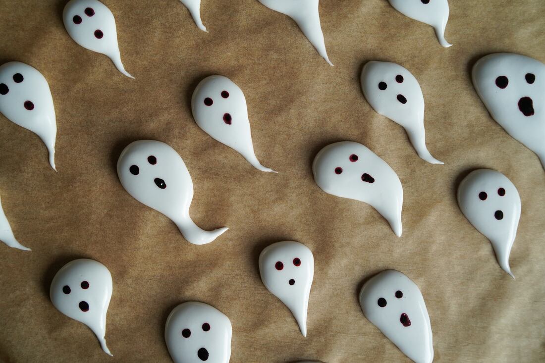 Fantasmas de merengue con ojos de chocolate sobre papel manteca